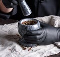 Cook in black latex gloves holding a stone mortar with pepper Royalty Free Stock Photo