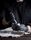 Cook in black latex gloves holding a stone mortar with pepper Royalty Free Stock Photo