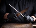 Cook in black latex gloves sharpens a knife Royalty Free Stock Photo