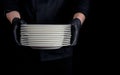 Cook in black uniform holds in his hands a stack of round white empty plates Royalty Free Stock Photo