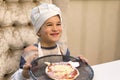 Cook boy. Little boy is a cook in flour in a white hat and apron in the kitchen preparing homemade pizza Royalty Free Stock Photo