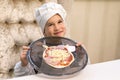 Cook boy. Little boy is a cook in flour in a white hat and apron in the kitchen preparing homemade pizza Royalty Free Stock Photo