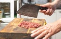 Cook chopping raw beef with a rustic kitchen cleaver on a wooden butcher block to make tartare, ground meat or minced meat, copy Royalty Free Stock Photo
