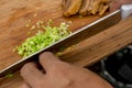 A cook chopping spring onions on a wooden board. With Lechon Carajay