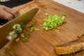 A cook chopping spring onions on a wooden board. With Lechon Carajay