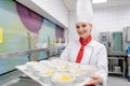 Cook in commercial kitchen showing tray with dessert