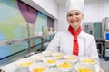 Cook in commercial kitchen showing tray with dessert