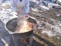 The cook cooks food on the street in a cauldron in winter on a bonfire and distributes it to the needy.