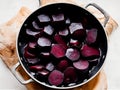 The cook cooks red beets in a saucepan