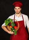 Cook with curious face holds veggies in basket.