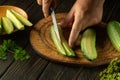 The cook cuts the cucumber with a knife into lengthwise pieces for pickling. Work environment on the kitchen table with cucumbers Royalty Free Stock Photo