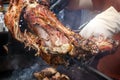 Cook cuts the finished lamb into pieces on a spit over hot coals