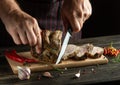The cook cuts grilled beef meat on a cutting board. Work environment on the kitchen table with condiments or spices. Dark Royalty Free Stock Photo