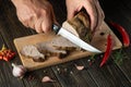 The cook cuts the grilled veal meat into small slices. Work environment on the kitchen table with condiments or spices. Black or Royalty Free Stock Photo