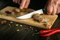 The cook cuts the meat sausage with a knife on the kitchen board. The national dish is prepared with spices on holidays. Delicious Royalty Free Stock Photo