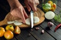 The cook cuts the onion with a knife on the kitchen cutting board. Peasant products for the preparation of preservation in a jar Royalty Free Stock Photo