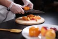 The cook cuts the persimmons and nectarines into slices. Assorted fruits and berries are cut into pieces. Unrecognizable photo. Royalty Free Stock Photo