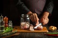 The cook cuts the raw fish into steaks and then cooks the herring in a jar. Working environment on the kitchen table with aromatic Royalty Free Stock Photo