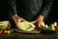 The cook cuts a ripe melon for table setting for a diet lunch. Fruit diet concept on black background