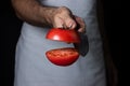 The cook cuts the tomato in half. Vegetarian cuisine.