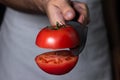 The cook cuts the tomato in half. Vegetarian cuisine.