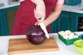 Closeup how Cook cutting red cabbage with white knife. Handsome man`s hand cut red cabbage. Closeup of red cabbage cut by knife. Royalty Free Stock Photo