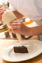 Cook decorating cake with whipped cream Royalty Free Stock Photo