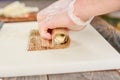 Cook in disposable gloves making sushi roll.