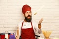 Cook with excited face in burgundy uniform sits by table Royalty Free Stock Photo