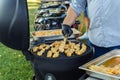 Cook flips grilled chicken kebabs in summer outdoors