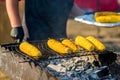 Cook in gloves fry corn on an open barbecue