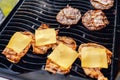 Cook grills burger patties and cheese pork ribs open fire. Turns meat over with tongs Royalty Free Stock Photo