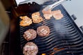 Cook grills burger patties and pork ribs open fire. Turns meat over with tongs Royalty Free Stock Photo