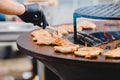 Cook grills steaks and pork ribs open fire. Turns meat over with tongs. Street food concept Royalty Free Stock Photo