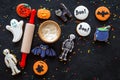 Cook halloween gingerbread cookies bat, skeleton, ghost. Sweets near rolling pin on black background top view copyspace