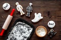 Cook halloween gingerbread cookies in shape of skeleton, ghost. Sweets near desk and rolling pin. wooden background top