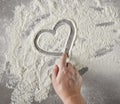 Cook hand drawing heart shape in flour