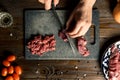 Cook hands cut red meat on the board. nearby are tomatoes, onion, butter Royalty Free Stock Photo