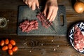 Cook hands cut red meat on the board. nearby are tomatoes, onion, butter Royalty Free Stock Photo