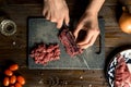 Cook hands cut red meat on the board. nearby are tomatoes, onion, butter Royalty Free Stock Photo