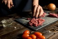 Cook hands cut red meat on the board. nearby are tomatoes, onion, butter Royalty Free Stock Photo