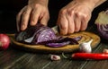 Cook hands with a knife cut red cabbage on a kitchen cutting board for salad. Cooking vegetarian food at home Royalty Free Stock Photo