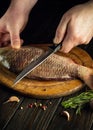 The cook hands with a knife on the kitchen table before cleaning the carp. Cooking a fish dish on the kitchen table with spices Royalty Free Stock Photo