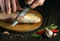 The cook hands with a knife on the kitchen table before cleaning the fish carp. Cooking a fish dish on the kitchen table with Royalty Free Stock Photo