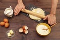 Cook hands rolling dough for baking with rolling pin on the board on wooden table Royalty Free Stock Photo