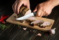 Cook hands are slicing grilled beef meat on cutting board. Work environment on kitchen table with condiments or spices. Royalty Free Stock Photo