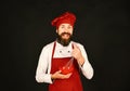 Cook with happy face in burgundy uniform holds bowl, whisk Royalty Free Stock Photo