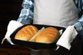 the cook holds a baking sheet with loaves of bread.