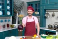 Cook holds red cabbage in hand on kitchen. Chef prepared fresh vegetables for cooking on the table. Happy guy in apron Royalty Free Stock Photo