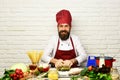 Cook with kind face in burgundy uniform sits by countertop